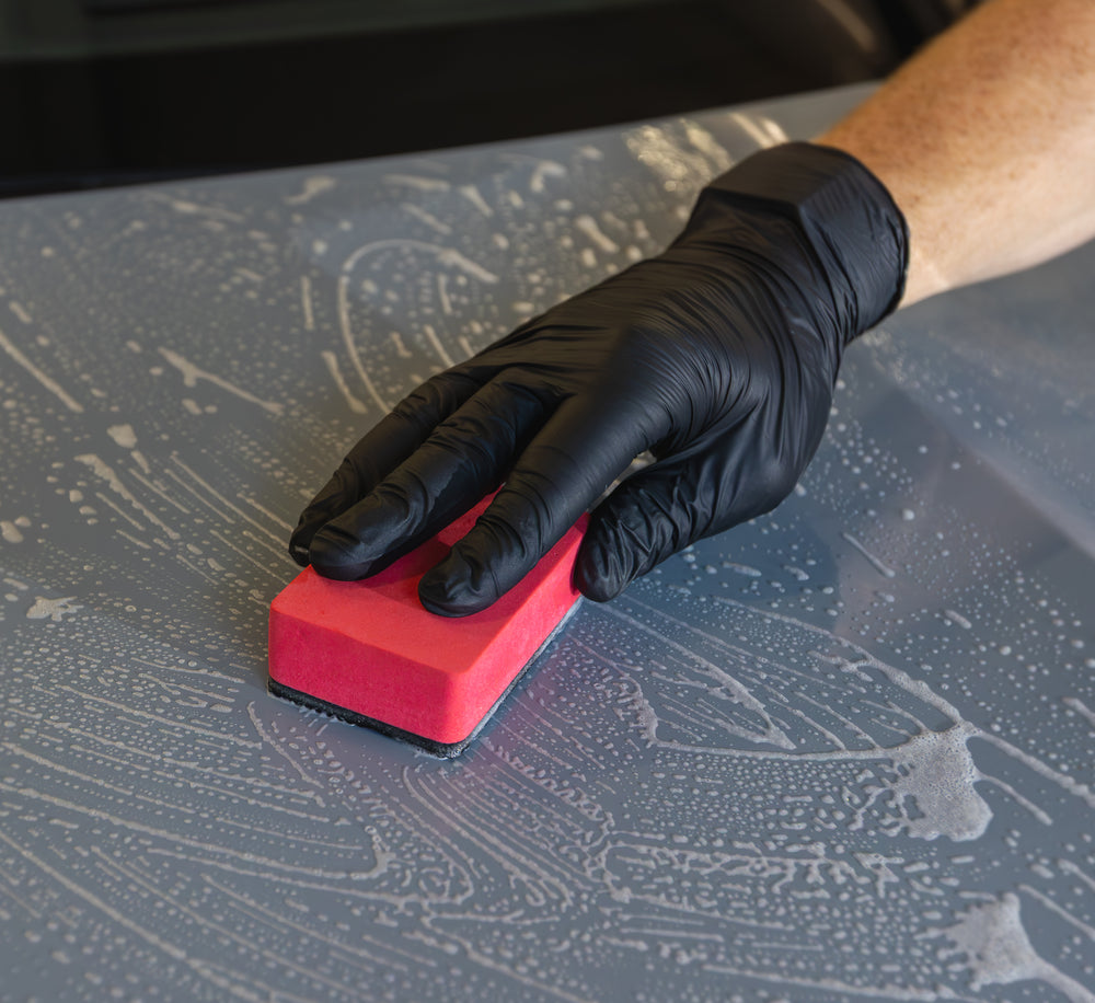 Rode Clay Sponge met polymeerzijde tijdens handmatige reiniging van natte lak